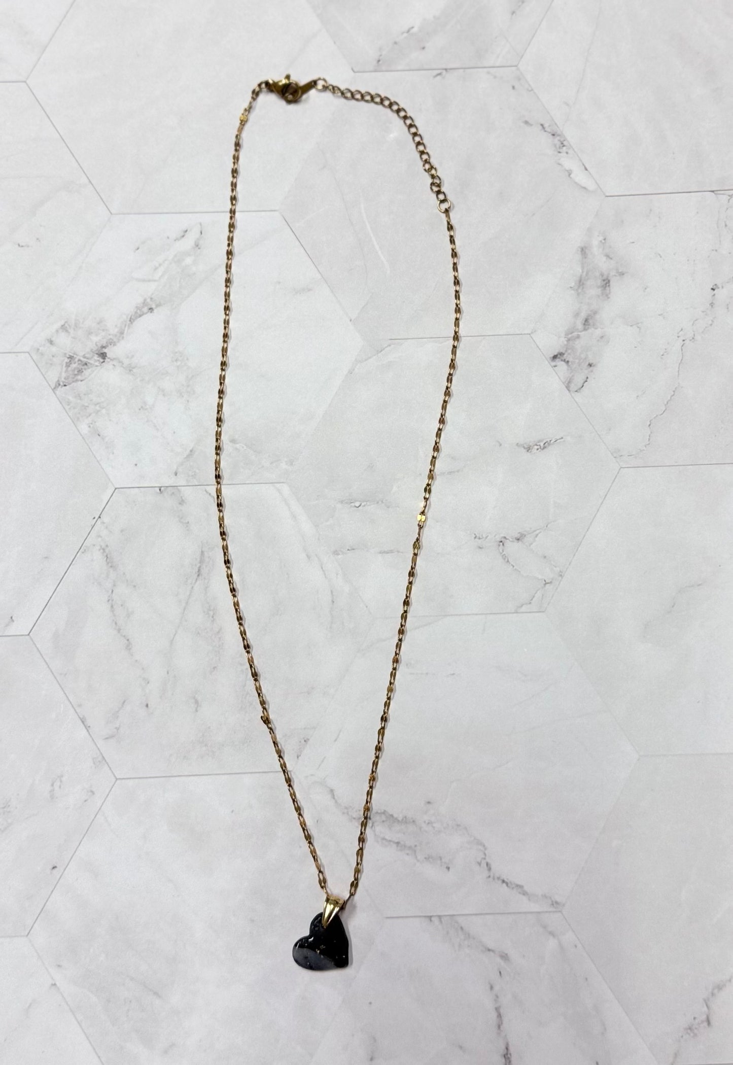 Collana pendente con ciondolo a forma di cuore, in porcellana fredda, colore nero con leggere sfumature, con catenina dorata.
Gioiello artigianale fatto a mano da persone cieche e ipovedenti.