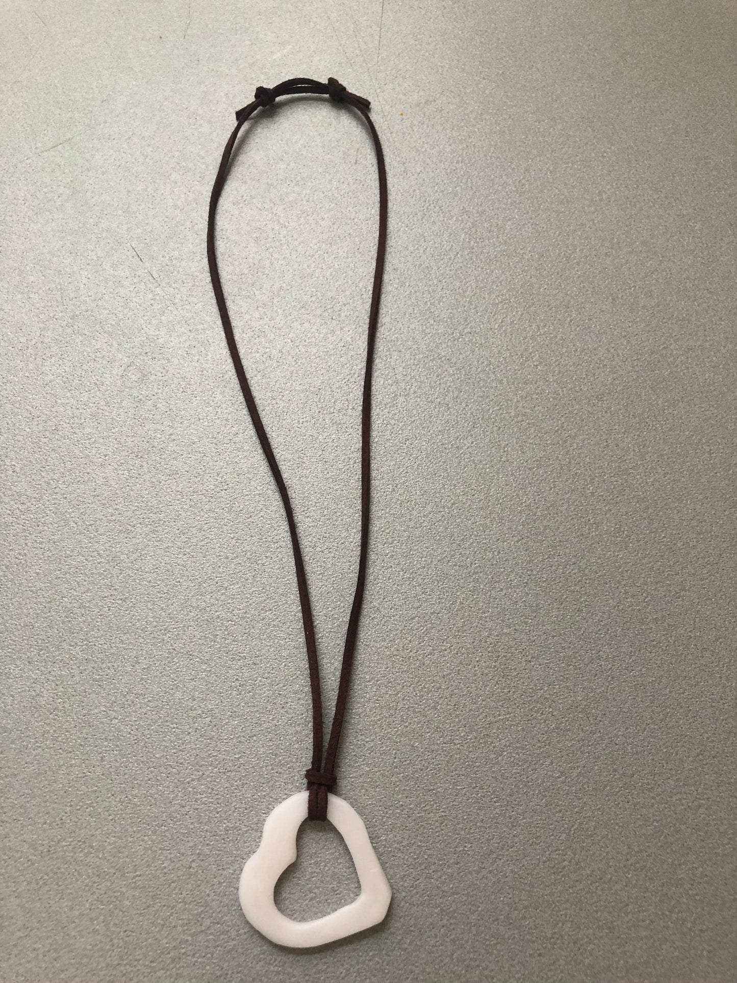 Collana “Cuore Piatto” collezione Asimmetrie, vista completa con ciondolo bianco a forma di cuore piatto e cordino marrone scuro regolabile.
