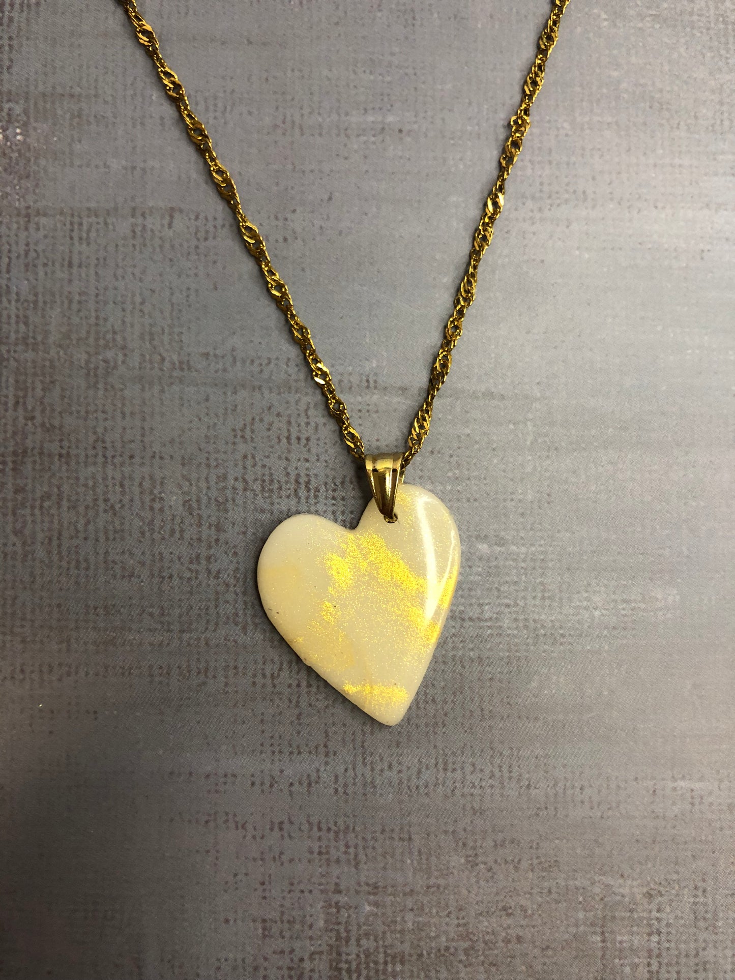 Collana pendente con ciondolo a forma di cuore, in porcellana fredda, colore bianco con dettagli in oro, con catenina dorata. 
Gioiello artigianale fatto a mano da persone cieche e ipovedenti.