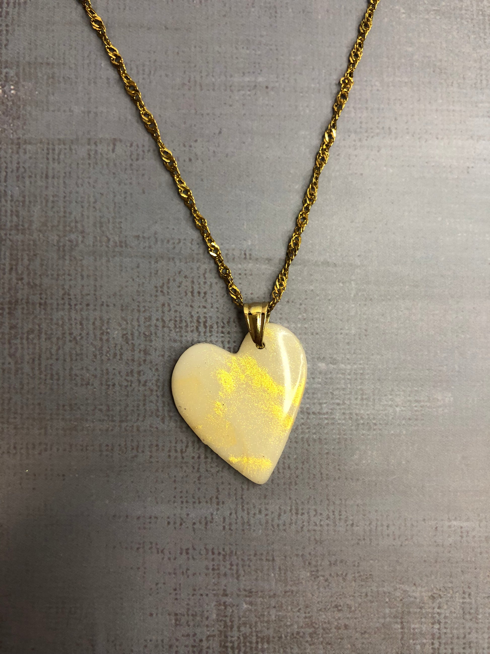 Collana pendente con ciondolo a forma di cuore, in porcellana fredda, colore bianco con dettagli in oro, con catenina dorata. 
Gioiello artigianale fatto a mano da persone cieche e ipovedenti.
