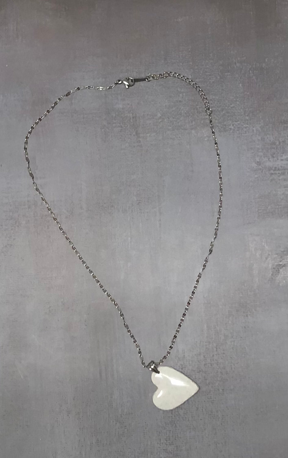 Intera collana pendente con ciondolo a cuore bianco a pois argentati, in porcellana fredda, stesa in tutta la sua lunghezza. Gioiello artigianale fatto a mano da persone cieche e ipovedenti.