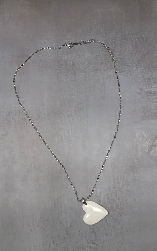 Intera collana pendente con ciondolo a cuore bianco a pois argentati, in porcellana fredda, stesa in tutta la sua lunghezza. Gioiello artigianale fatto a mano da persone cieche e ipovedenti.