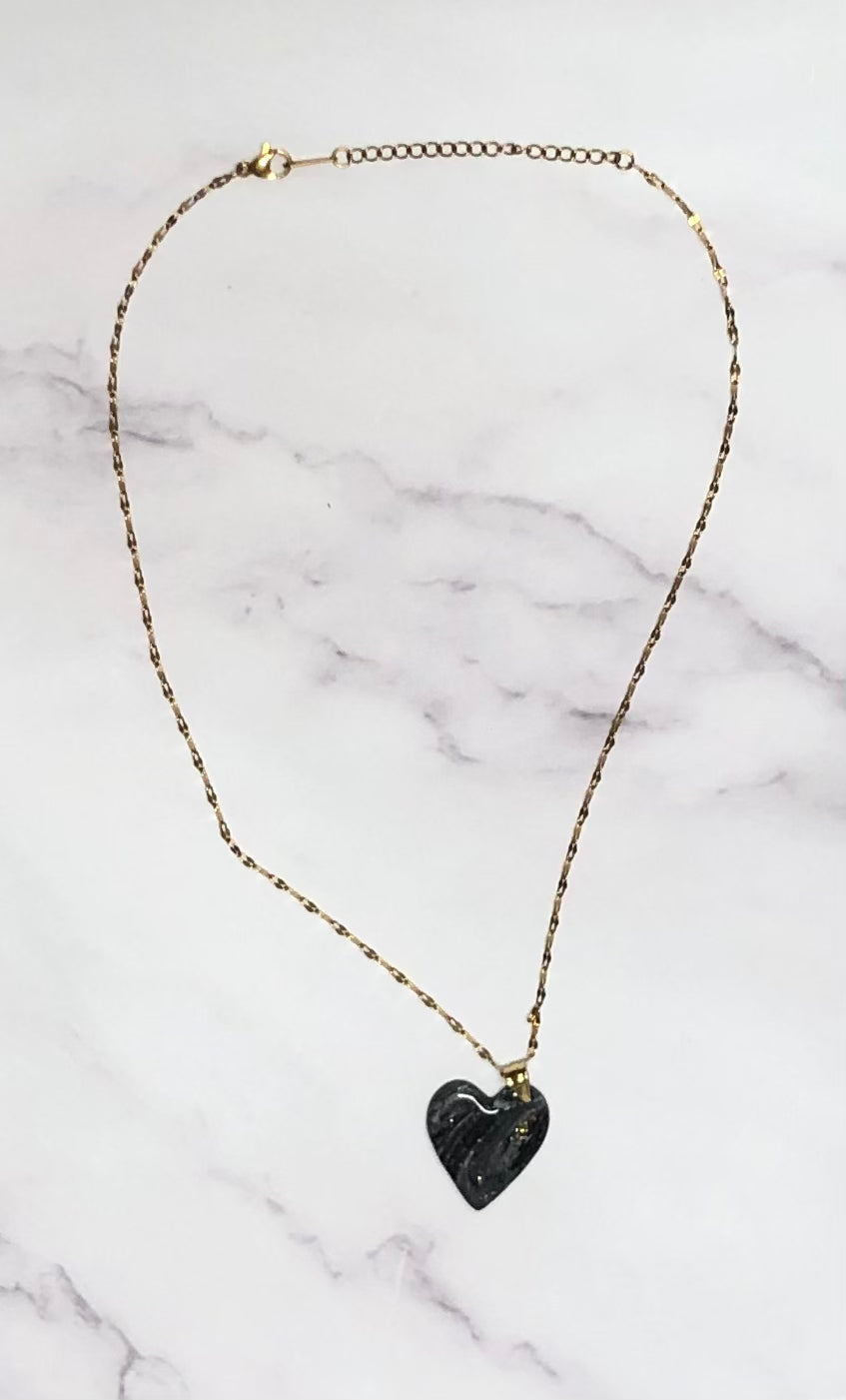 Collana pendente con ciondolo a forma di cuore, in porcellana fredda, colore nero dorato, con catenina dorata. 
Gioiello artigianale fatto a mano da persone cieche e ipovedenti.