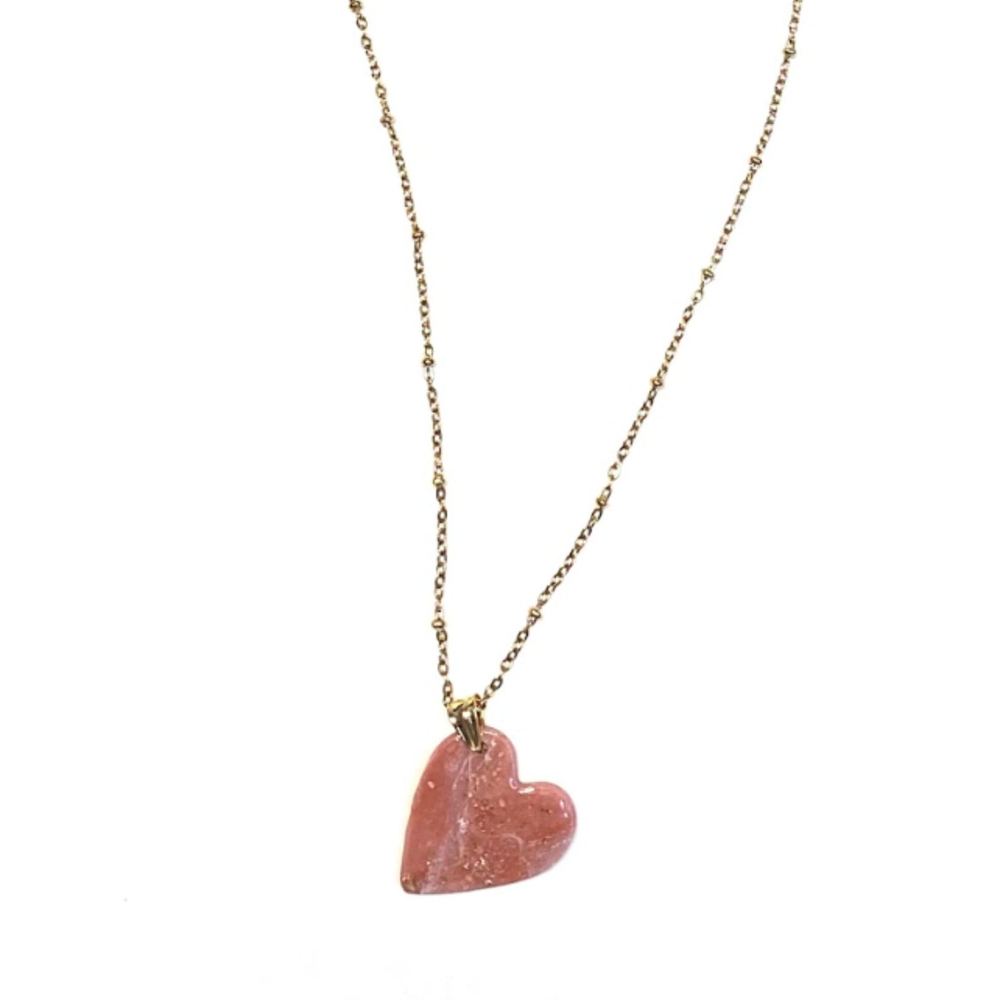 Collana pendente con ciondolo a forma di cuore, in porcellana fredda, colore rosa e bianco, con dettagli oro, effetto marmo, con catenina dorata. 
Gioiello artigianale fatto a mano da persone cieche e ipovedenti.