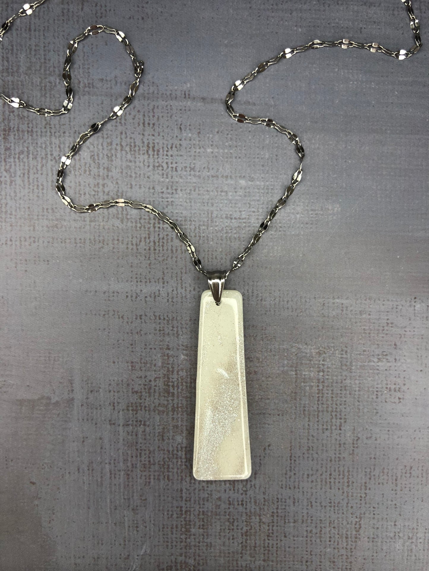 Collana pendente con ciondolo rettangolare, in porcellana fredda, colore bianco con dettagli in argento, con catenina argentata. 
Gioiello artigianale fatto a mano da persone cieche e ipovedenti.