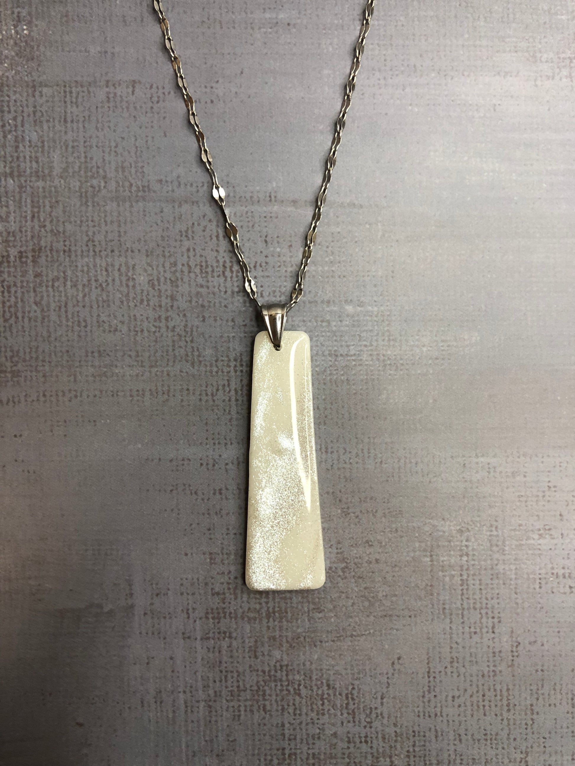 Collana pendente con ciondolo rettangolare, in porcellana fredda, colore bianco con dettagli in argento, con catenina argentata. 
Gioiello artigianale fatto a mano da persone cieche e ipovedenti.