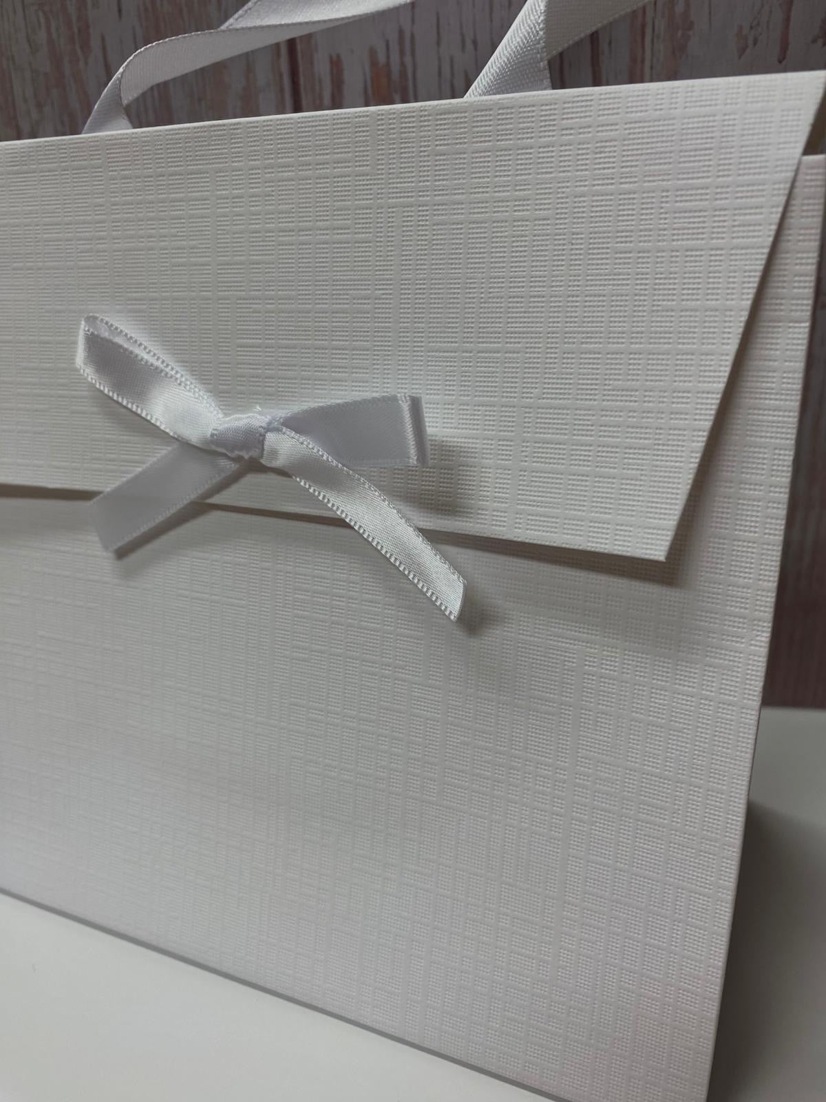 Borsa regalo bianca in cartoncino rigido con texture a rilievo e fiocco in raso bianco.