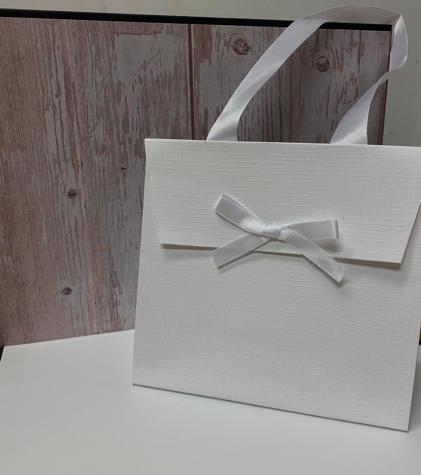Borsa regalo bianca in cartoncino rigido con texture a rilievo e manici in raso.