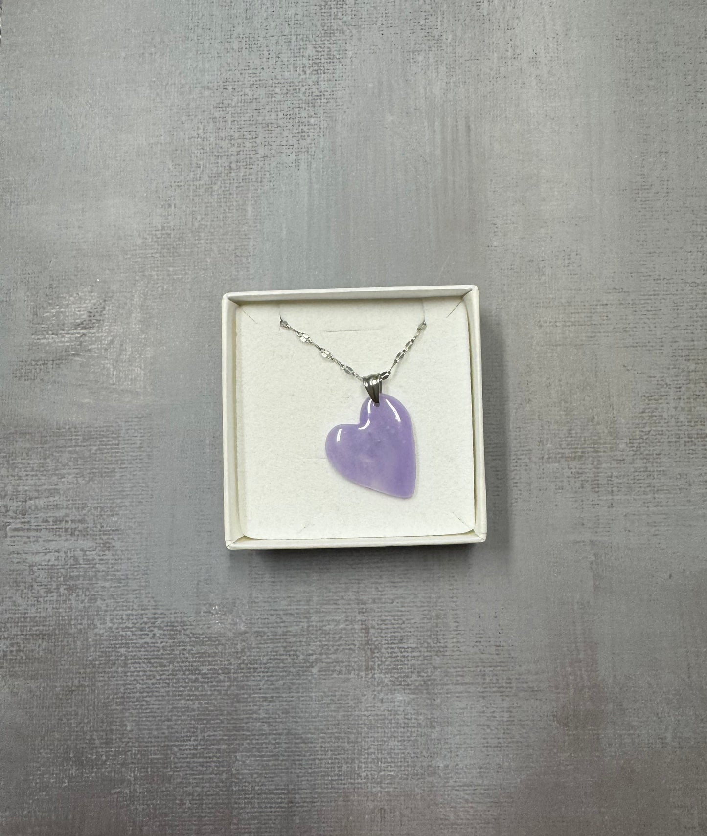 Confezione regalo aperta Myra Lab con collana pendente a cuore lilla con sfumature. Catenina argentata. Gioiello artigianale fatto a mano da persone cieche e ipovedenti.