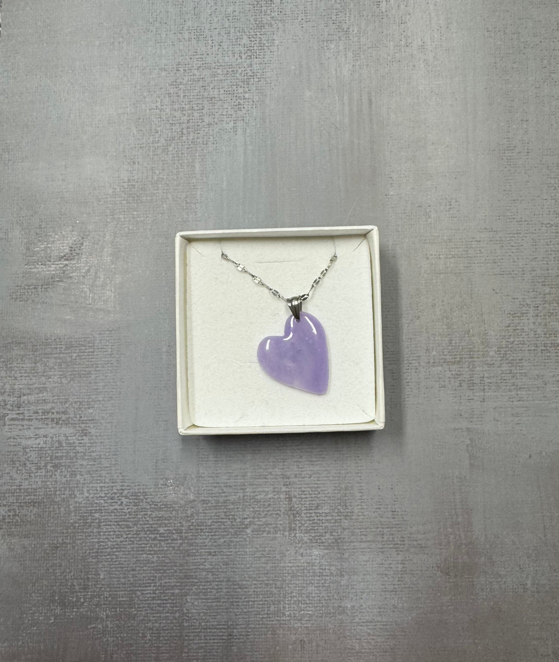 Confezione regalo aperta Myra Lab con collana pendente a cuore lilla con sfumature. Catenina argentata. Gioiello artigianale fatto a mano da persone cieche e ipovedenti.