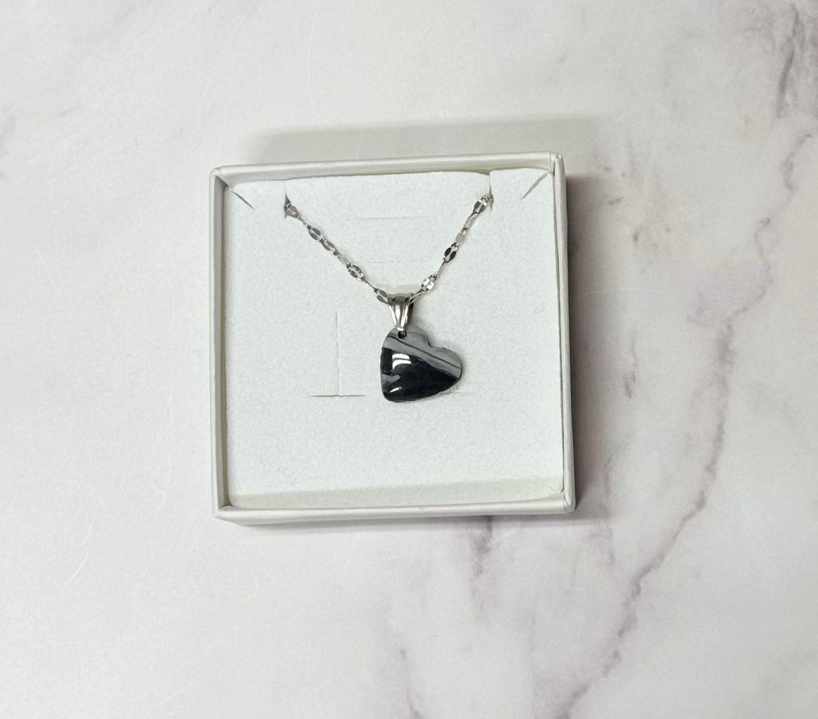 Collana pendente con ciondolo a forma di cuore, in porcellana fredda, colore nero e bianco, con catenina argentata. 
Gioiello artigianale fatto a mano da persone cieche e ipovedenti. 