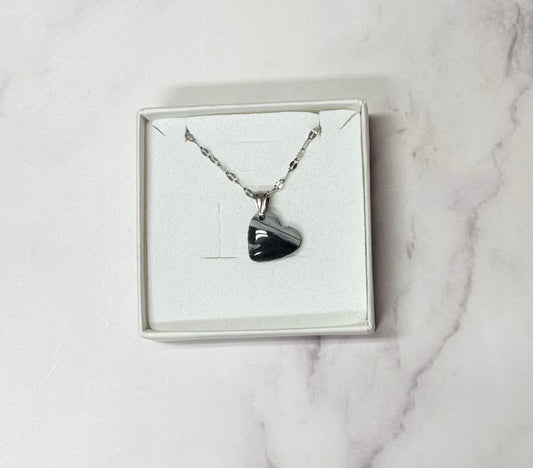 Collana pendente con ciondolo a forma di cuore, in porcellana fredda, colore nero e bianco, con catenina argentata. 
Gioiello artigianale fatto a mano da persone cieche e ipovedenti. 