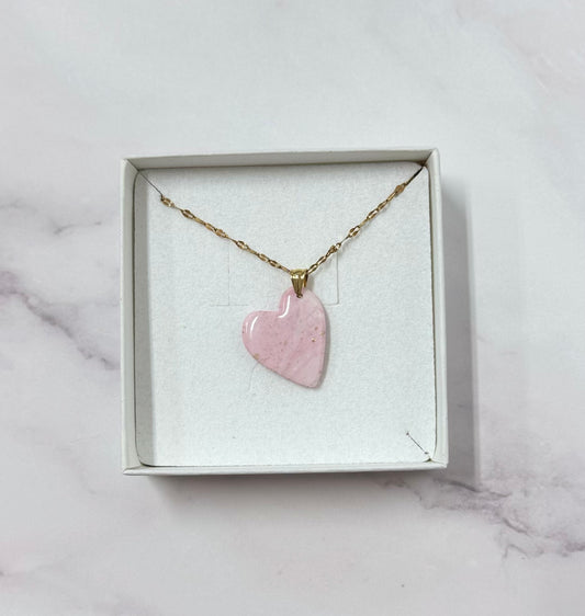 Confezione originale Myra Lab aperta, contenente la collana con ciondolo a forma di cuore, rosa, in porcellana fredda. Gioiello artigianale realizzato da persone cieche e ipovedenti.