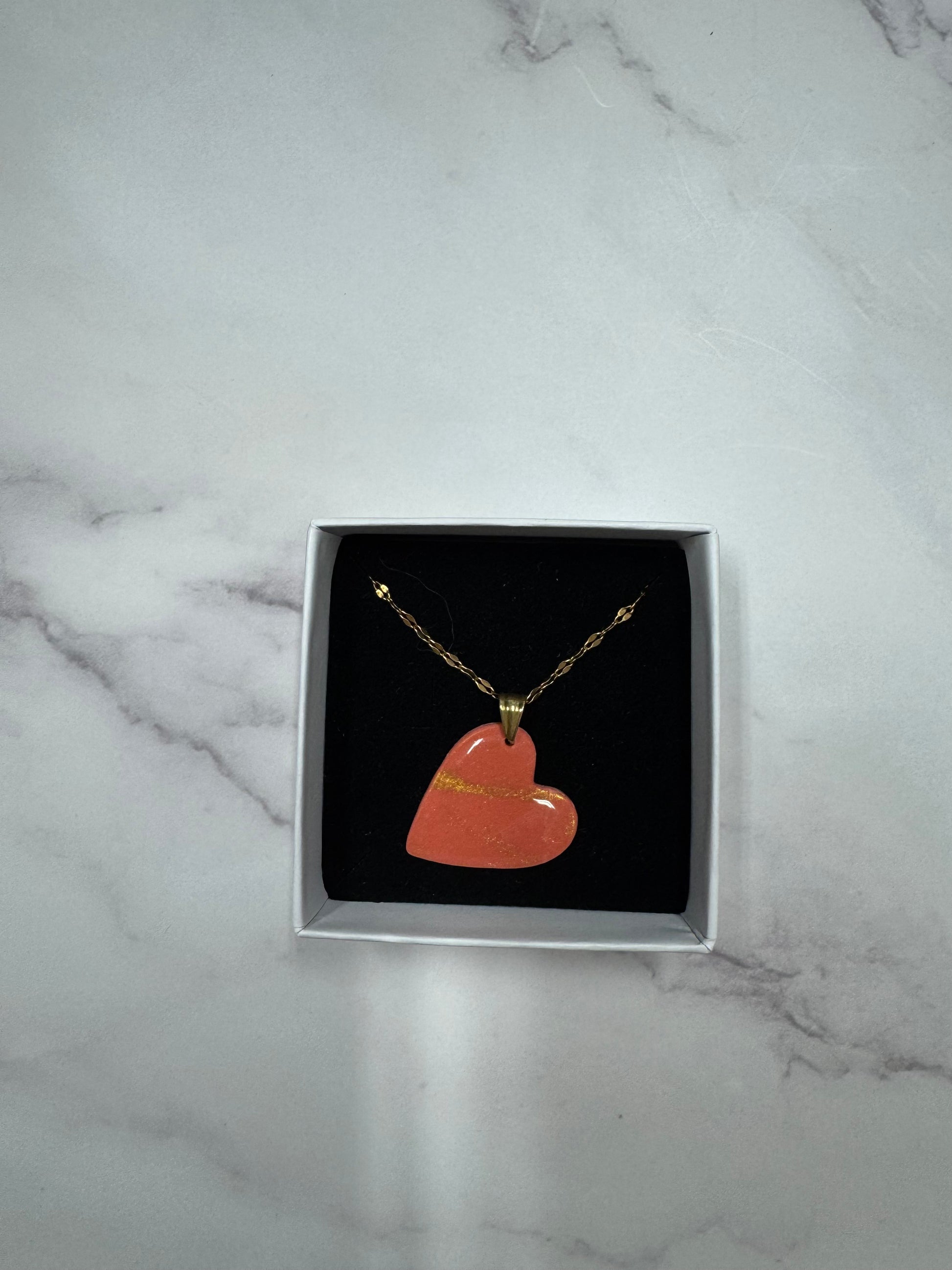 Confezione originale Myra Lab aperta, contenente la collana con cuore rosso in porcellana fredda. Gioiello artigianale realizzato da persone cieche e ipovedenti.