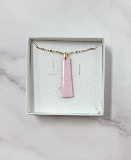 Confezione originale Myra Lab aperta, contenente la collana con ciondolo a forma di rettangolo rosa in porcellana fredda. Gioiello artigianale realizzato da persone cieche e ipovedenti.